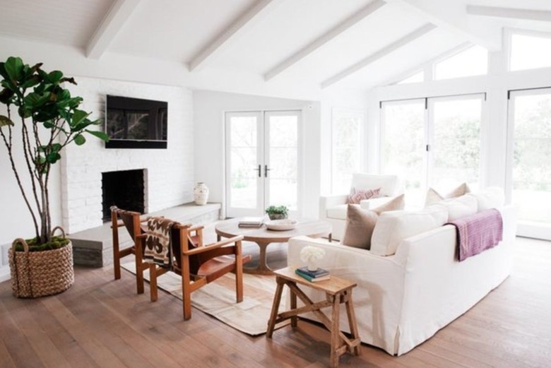 Ranch style living room with white brick fireplace, white couch, large plant, white beam ceiling