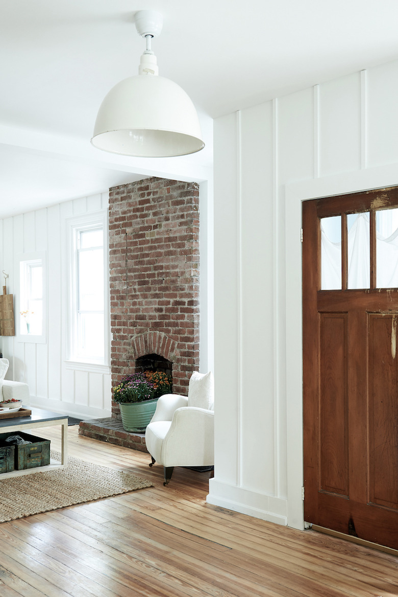 White board and batten farmhouse living room with exposed brick fireplace.