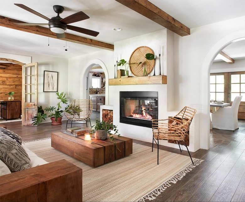 Farmhouse style living room with fireplace, wood beams, ceiling fan.