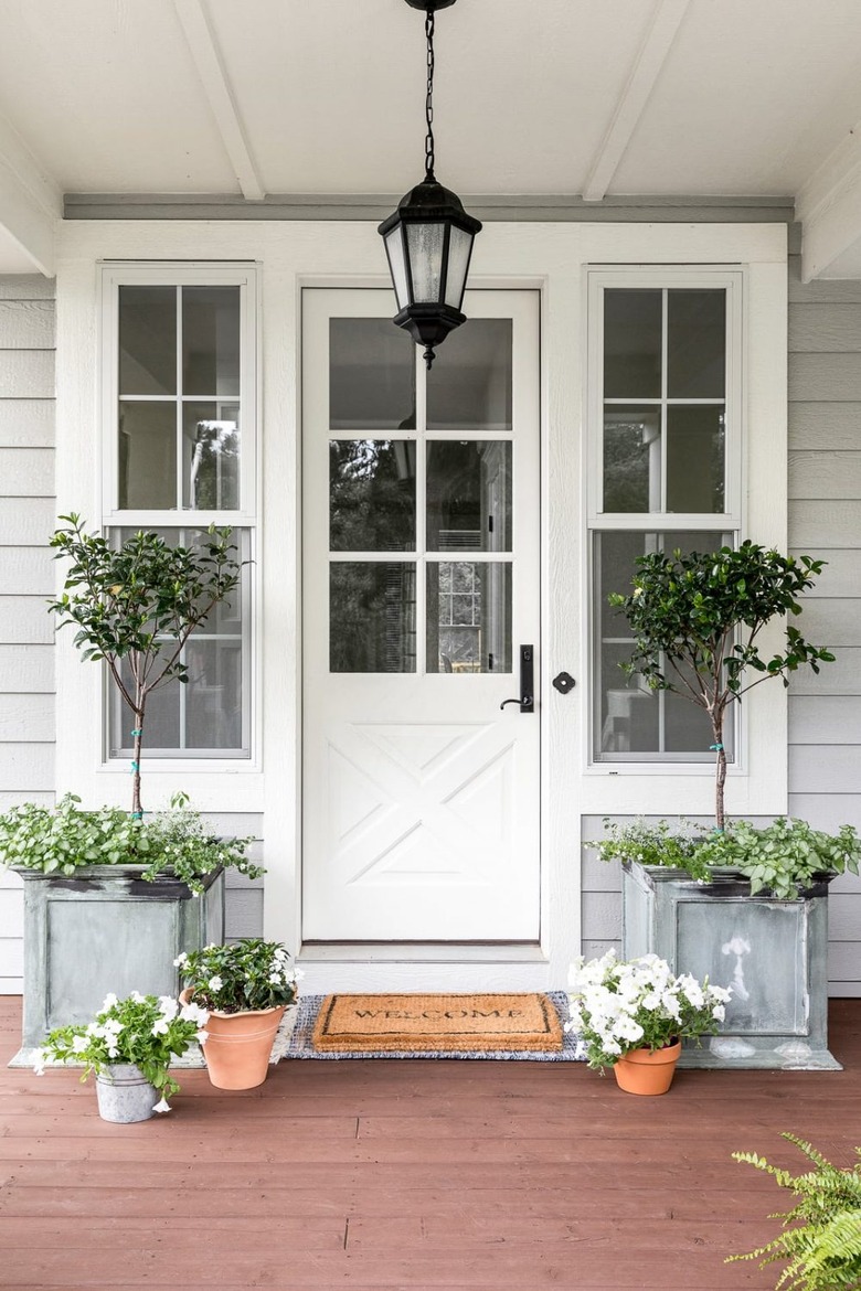 Farmhouse front door idea in white with pendant light lantern and greenery