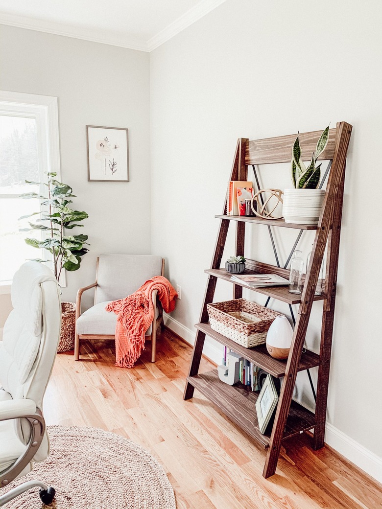 Farmhouse home office with ladder shelf and chair in corner with orange blanket