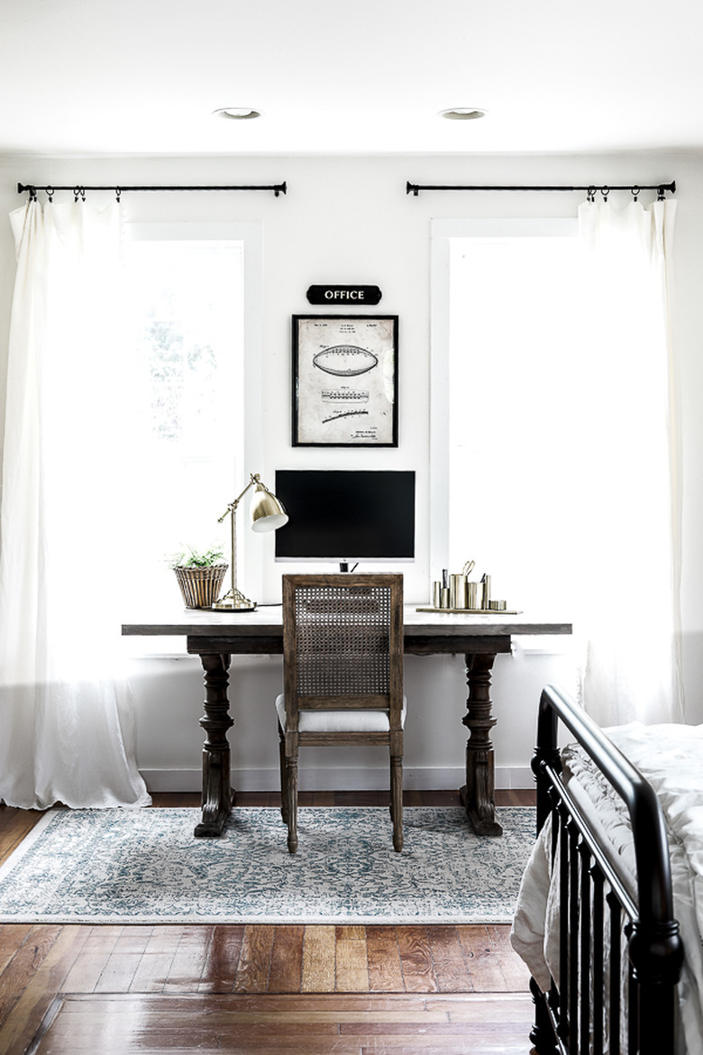 Farmhouse home office in bedroom with wood desk and wall art