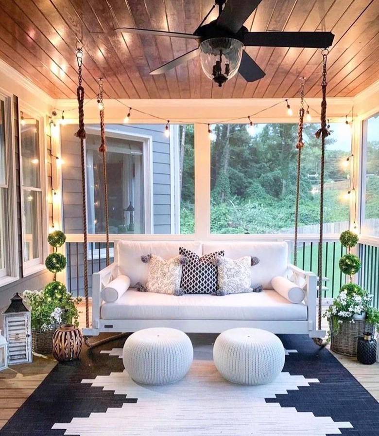 covered porch with string lights and hanging sofa