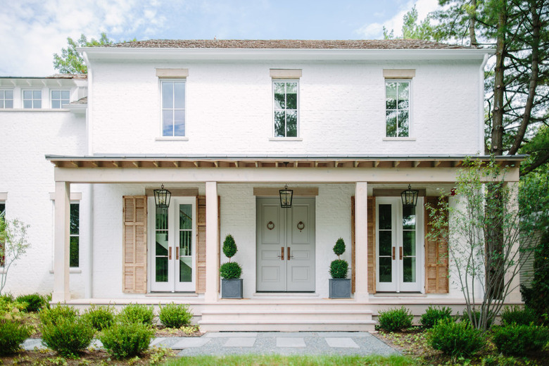 farmhouse porch idea with hanging lanterns and vintage wood shutters flanking French doors and gray-green front doors