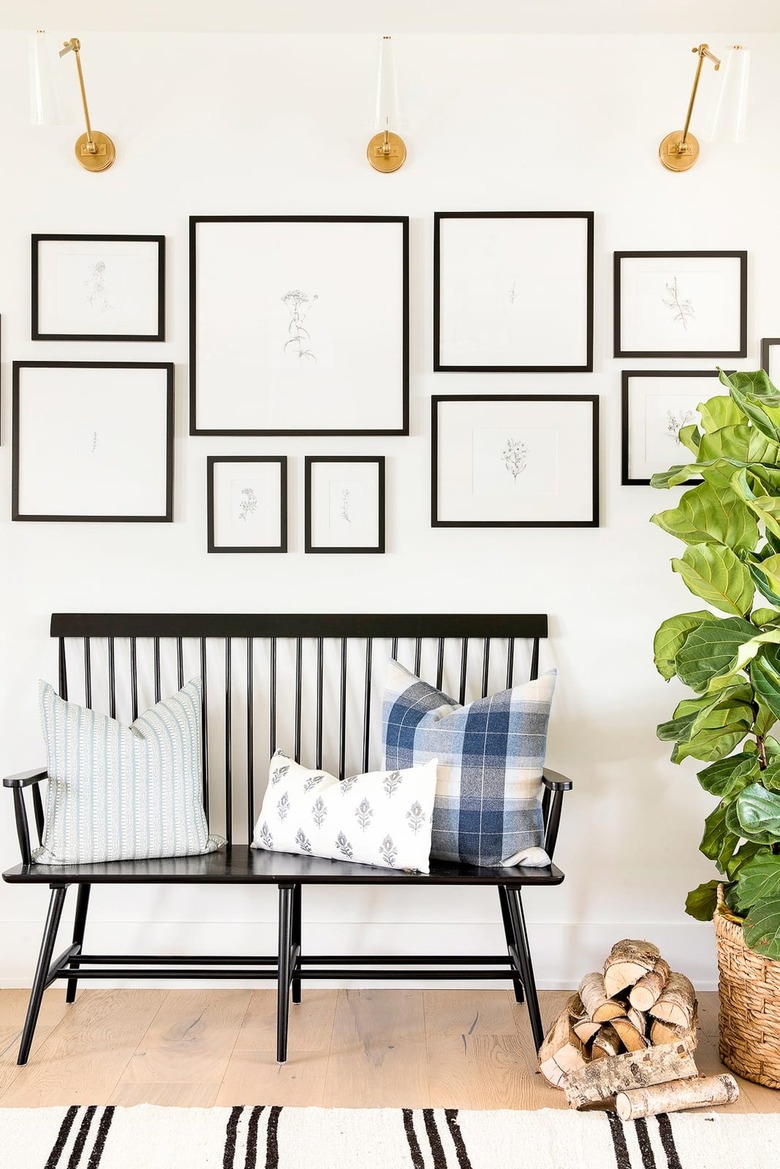 black and white gallery wall with brass sconces and bench