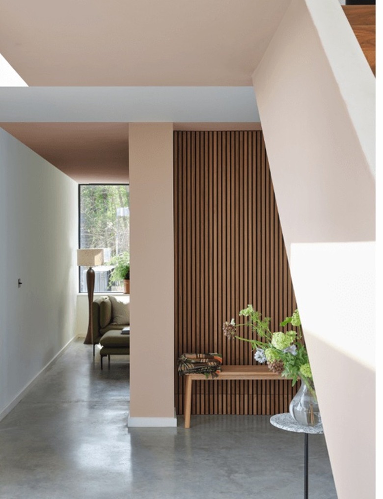 Farrow & Ball's light pink paint color in an entryway next to a staircase with a bench and side table underneath it.