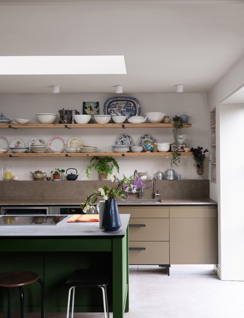 Farrow & Ball beige paint color on a kitchen wall behind open wood shelving covering in various plates and bowls.