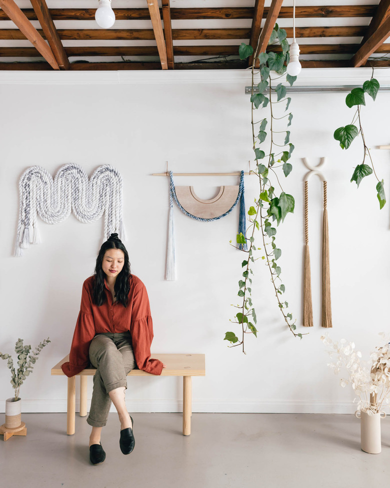 figure sitting on a bench near wall hangings