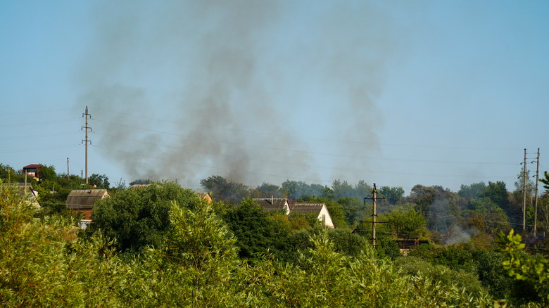 Fire in the house. The house was damaged by fire. Smoke from the roof of a burning house. Remains of a burned down house.