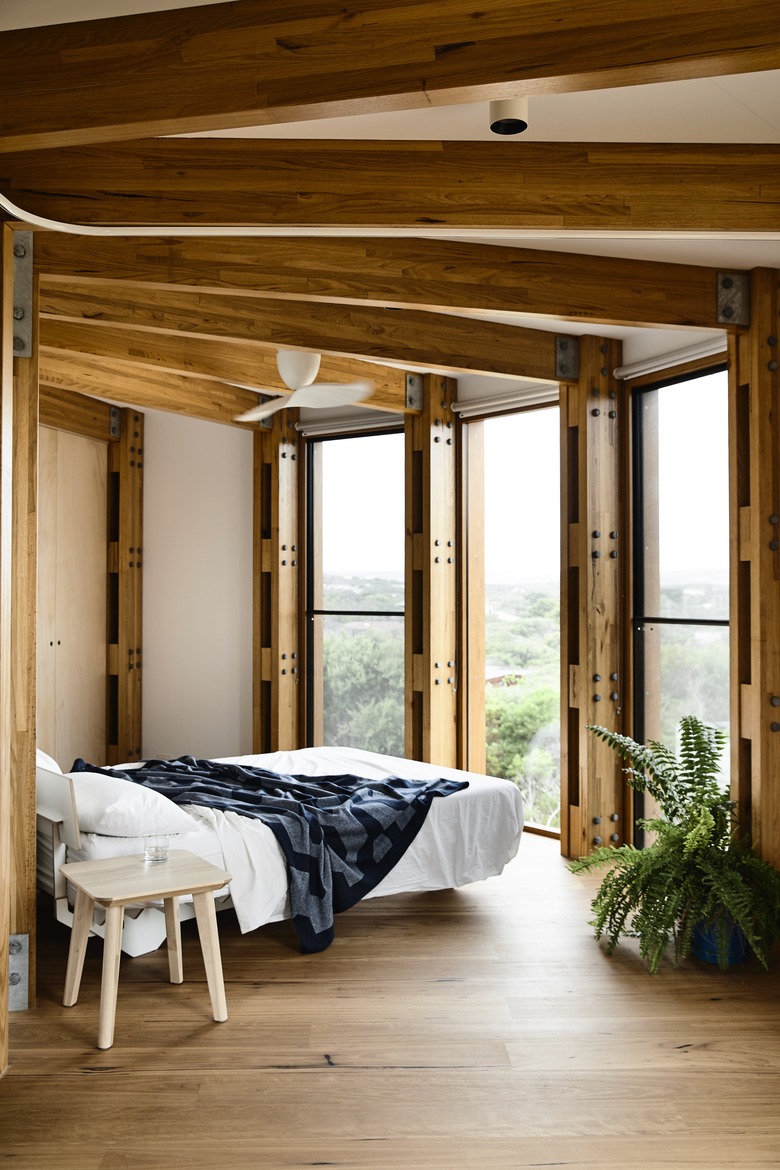 wooden bedroom with floor to ceiling windows and bed