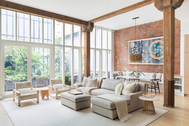 large loft with a wall of floor to ceiling windows and exposed brick wall