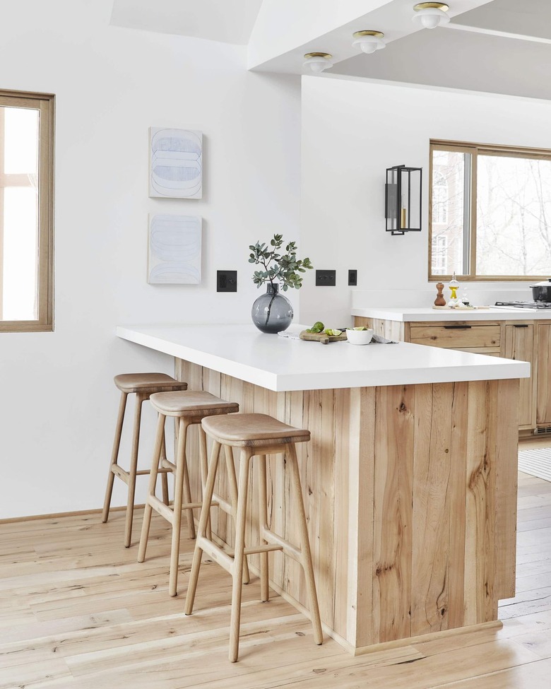 white kitchen with wooden detailed island and three flush mount light fixtures hanging above it