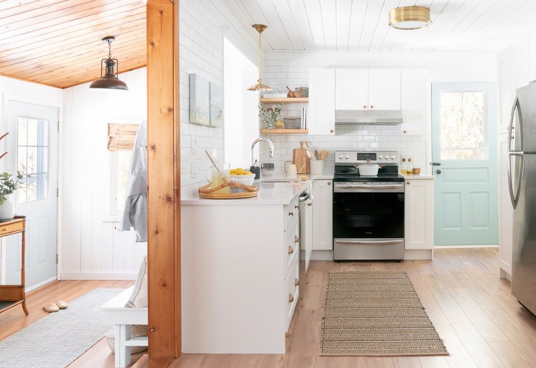 white kitchen with brass flush mount light fixture and a turqouise door