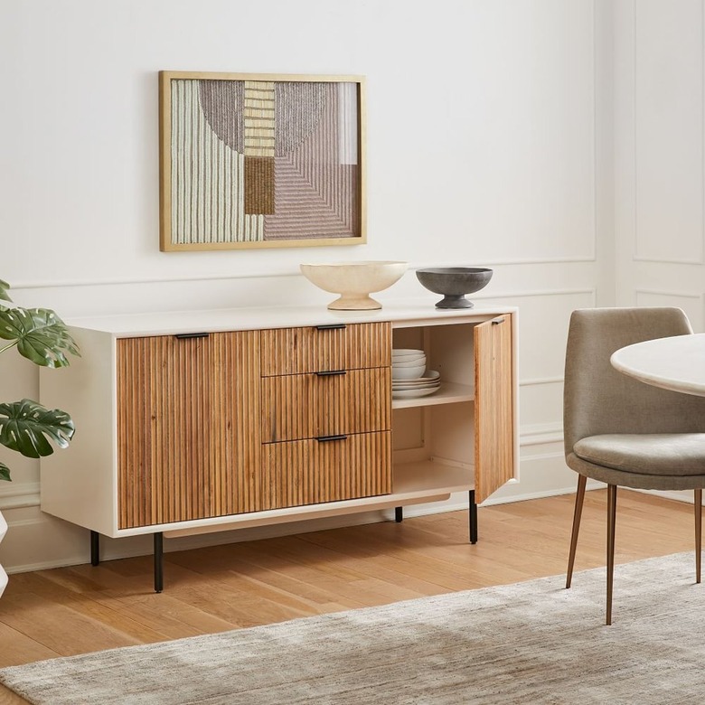 fluted buffet table with artwork and chair nearby