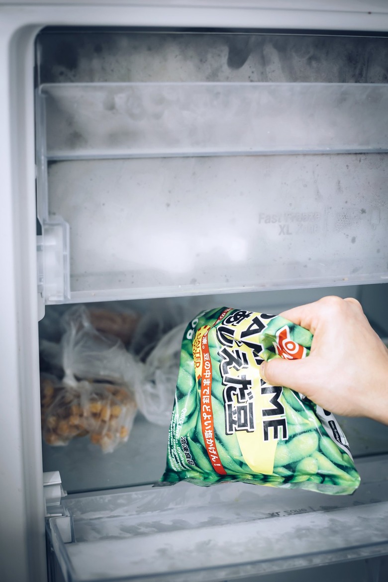 Hand removing frozen peas from freezer