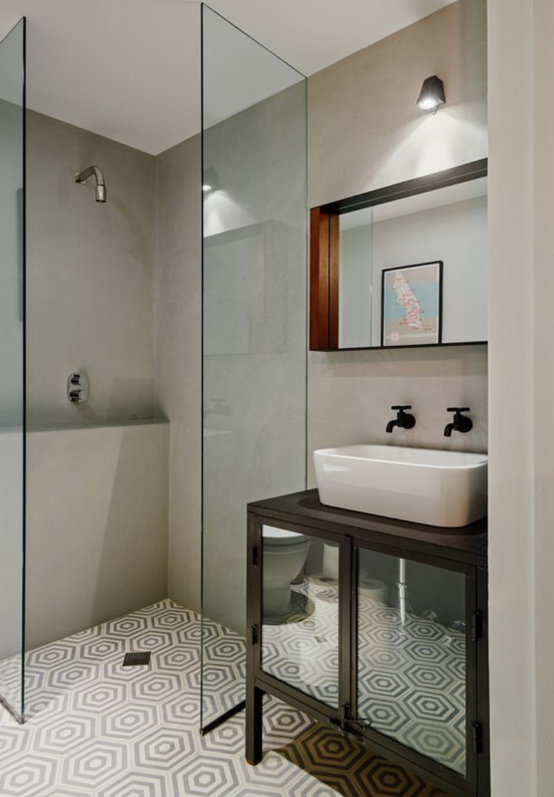 Frameless and doorless shower in bathroom with cement hexagon tile.