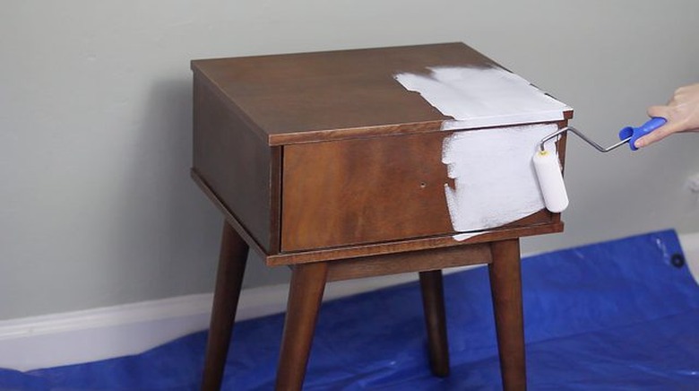 white paint being applied to wood bedside table