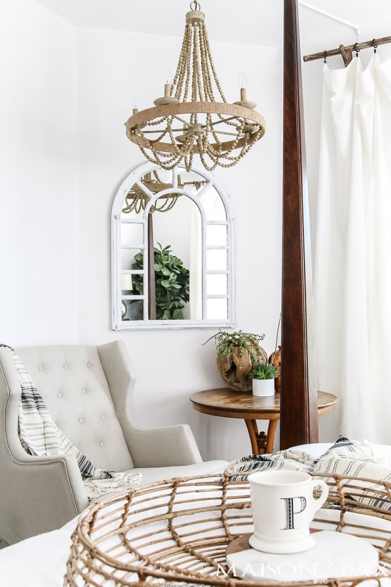 Neutral colors in French country bedroom with beaded chandelier