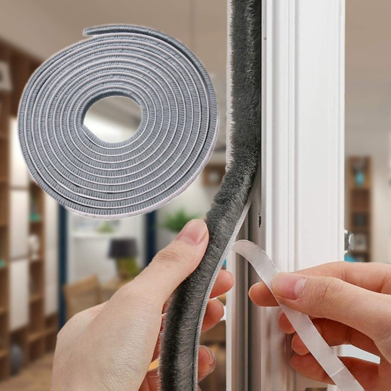 A woman replaces weatherstripping on a door