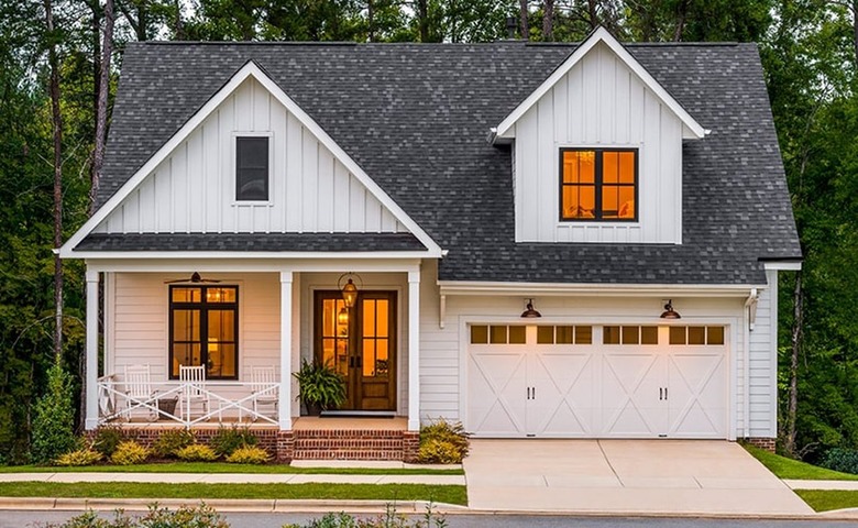 A white barn-style garage door on a white house