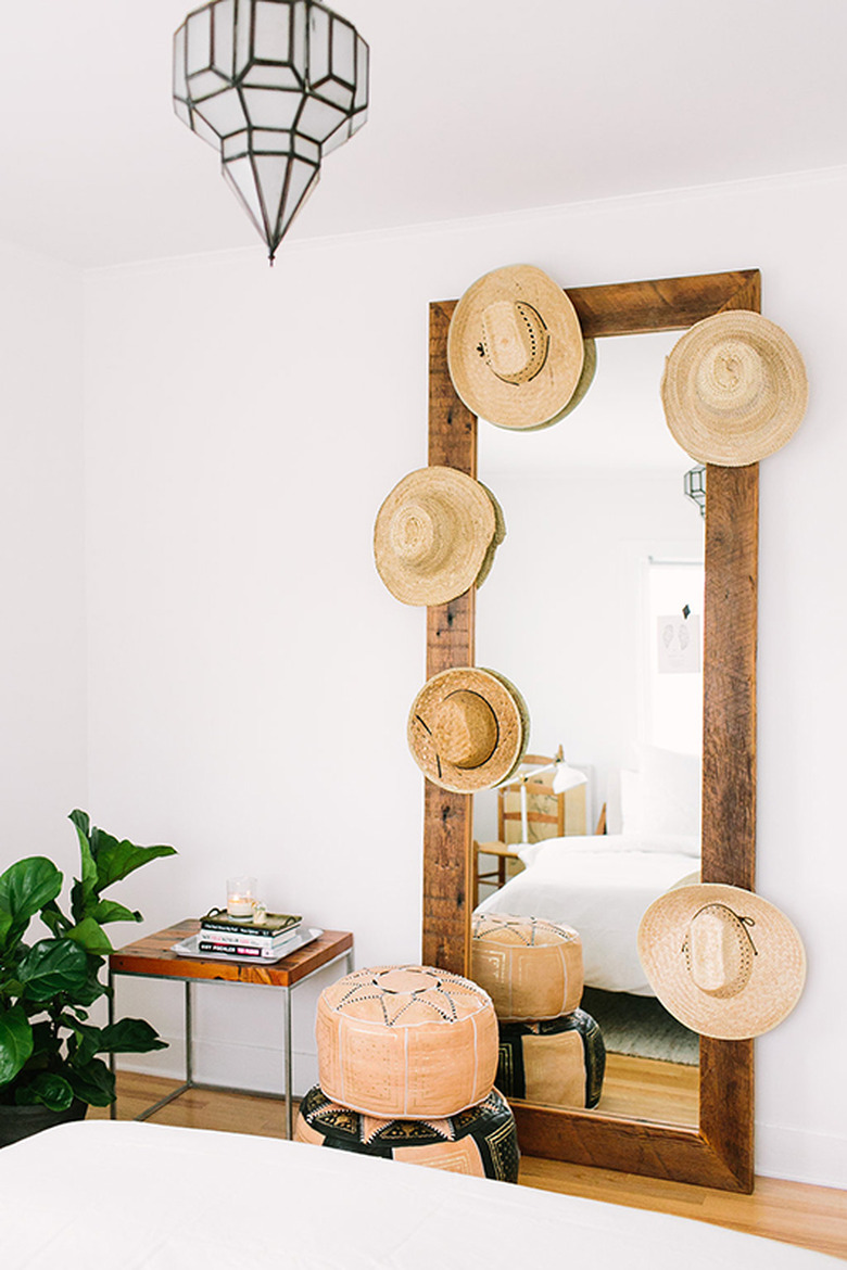 hats hung on leaning mirror frame