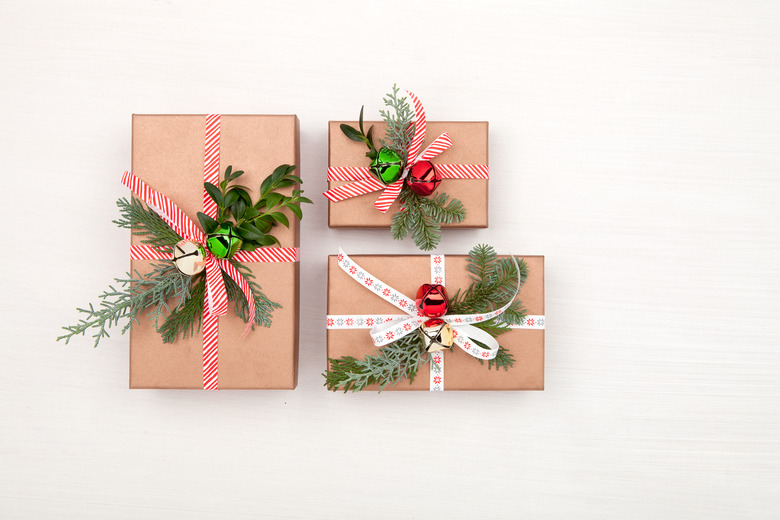 Christmas gift boxes decorated fir tree branches and bells on white background. Christmas, winter, New Year concept. Flat lay, top view, copy space