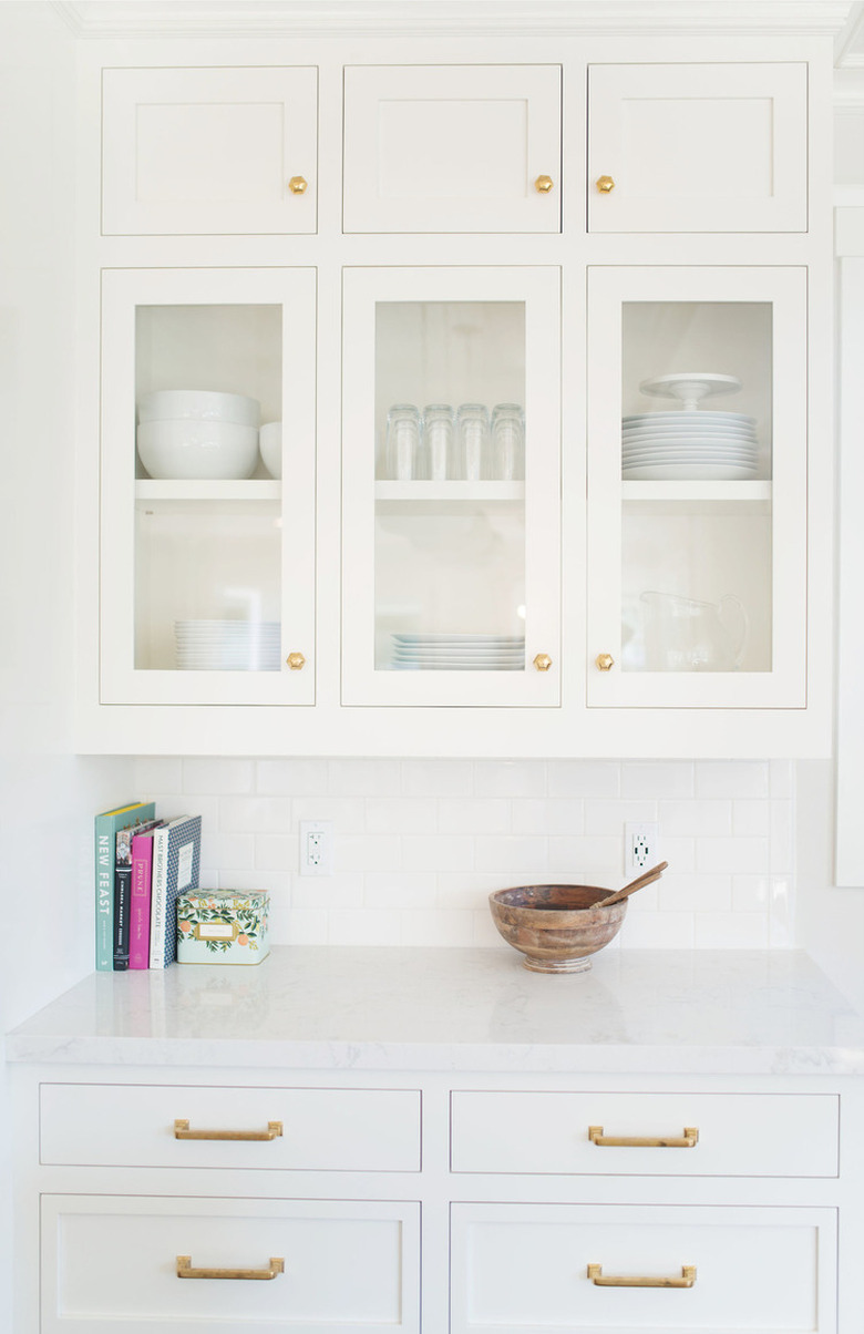 white kitchen cabinets with wood bowl and books on countertop