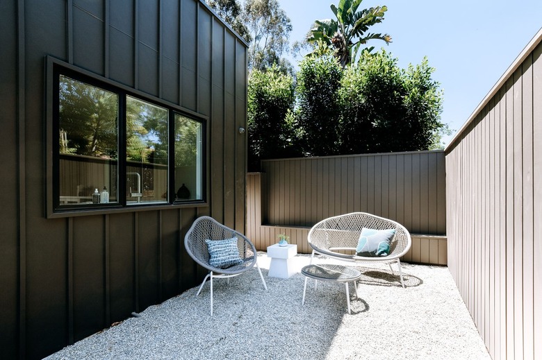 Modern white outdoor furniture in patio made of gravel and stones.