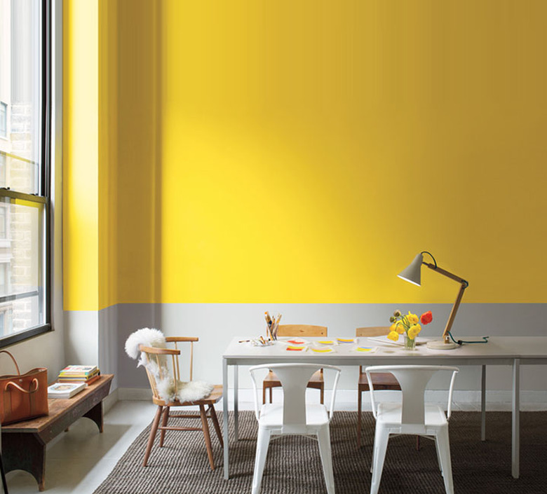 yellow and gray wall with long table and white chairs