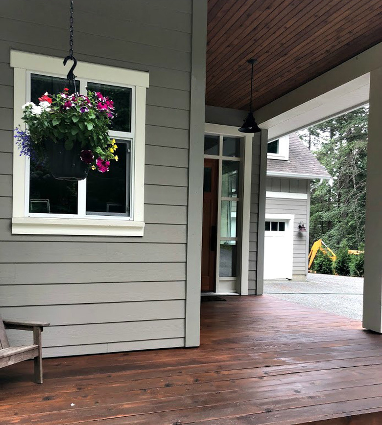 gray exterior paint with stained porch and hanging flowers