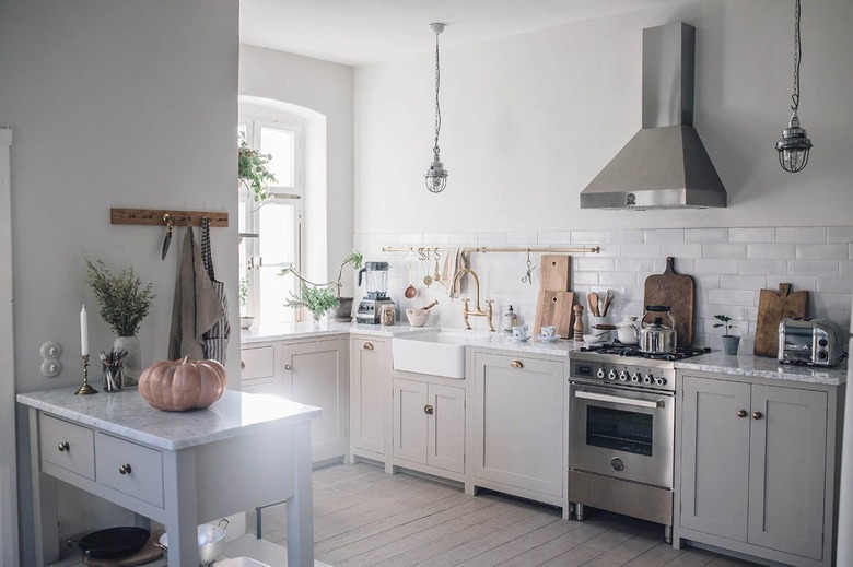 small gray kitchen island made of wood with two drawers in area with exposed range hood