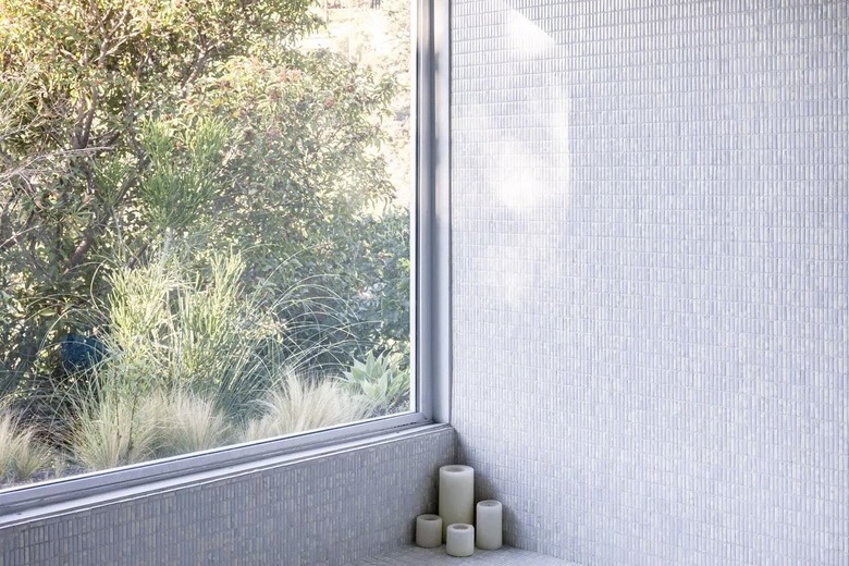 gray tiled bathroom wall with large window and arrangement of pillar candles