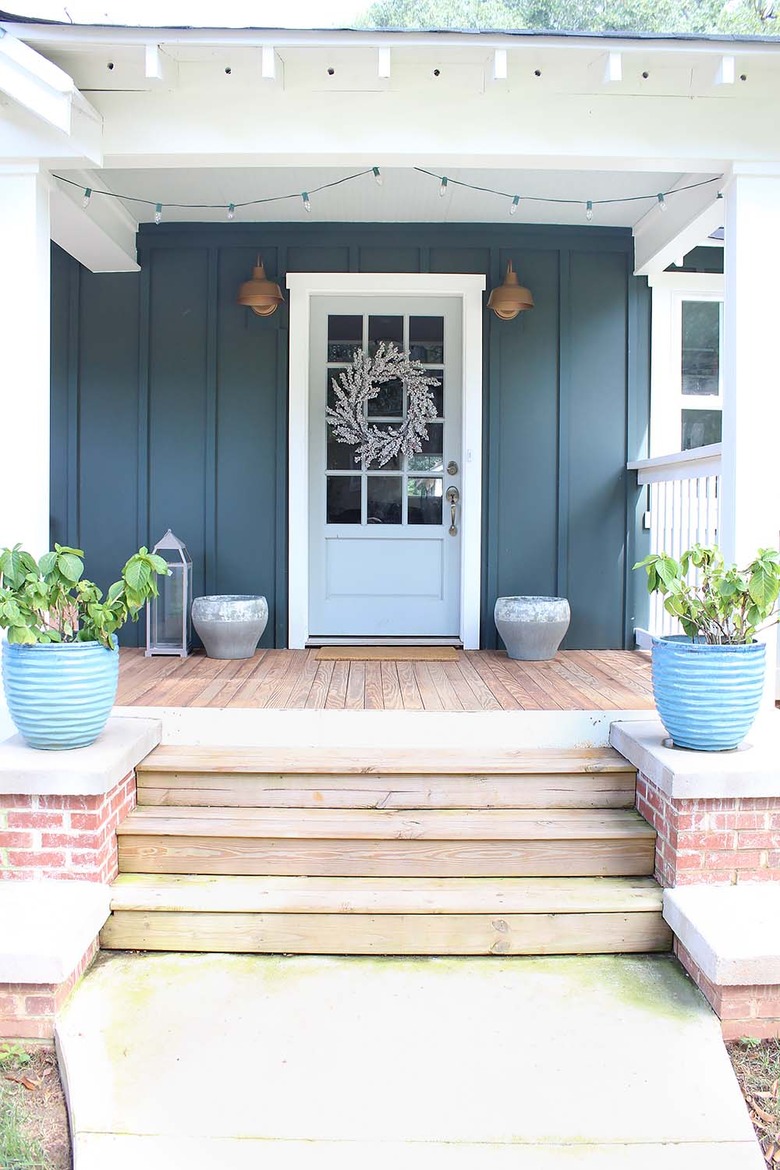 Teal green exterior house paint with farmhouse decor and brass barn lights