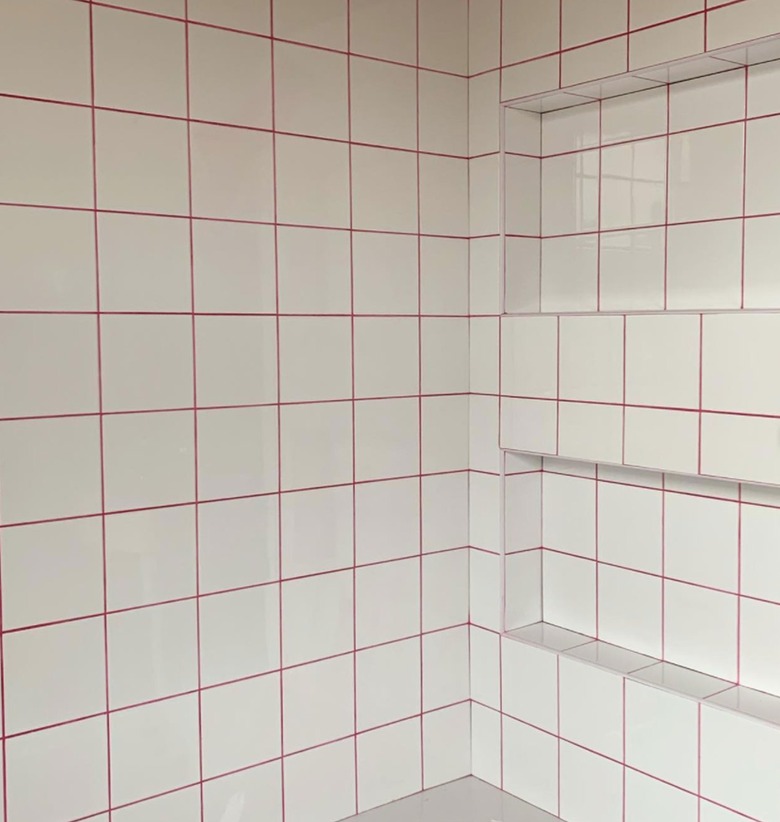 Shower with white square tile, hot pink grout.