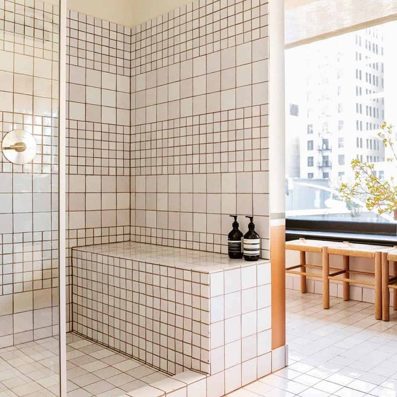 Off white tile in a shower with brown grout.