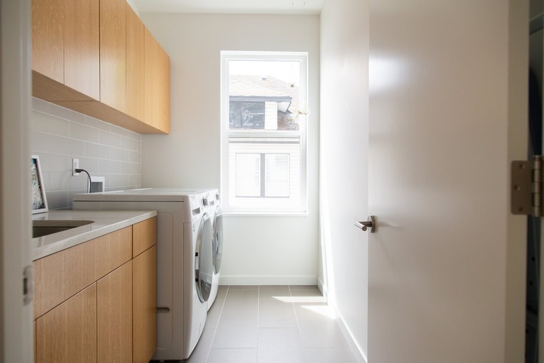 Minimalist laundry room with wood cabinets and white walls