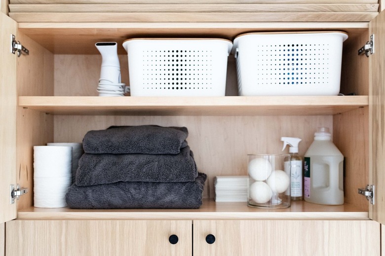 laundry storage on wood shelving with white bins and glass canisters