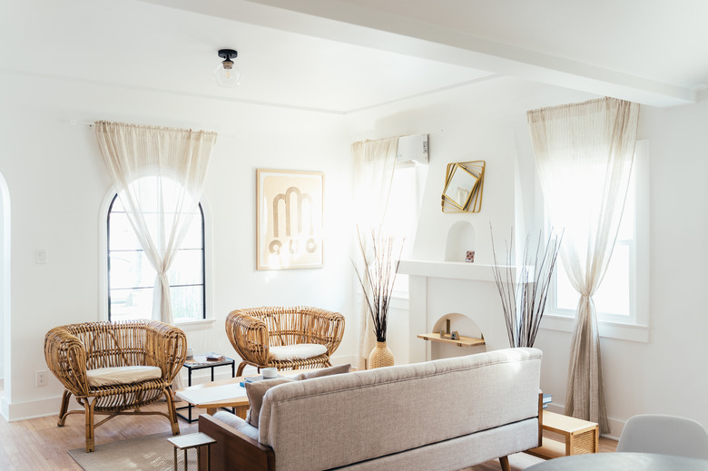 white color idea in living room with rattan lounge chairs, blush sofa and wood accents