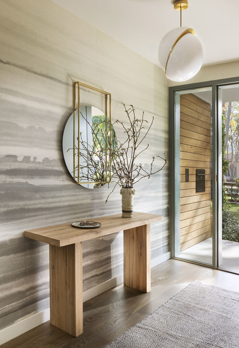 A not so neutral look in a California modern hallway, with console table, round mirror, and pendant light.