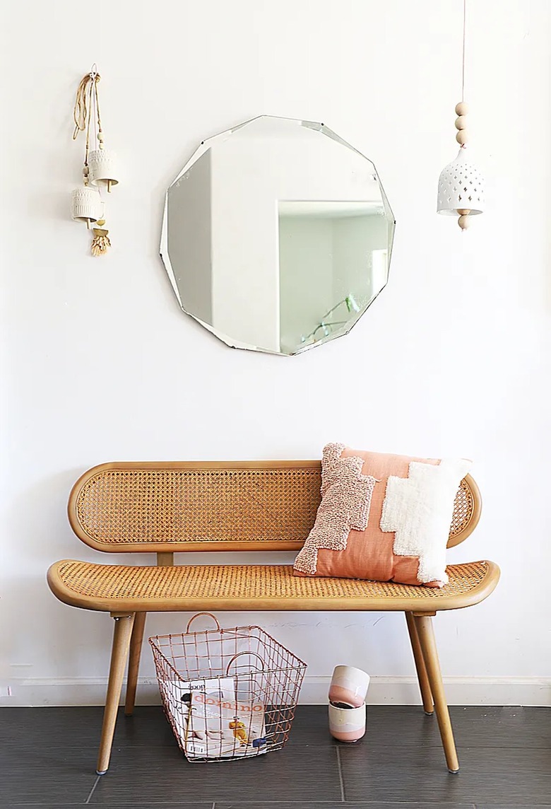 cane bench and pink throw pillow in entryway