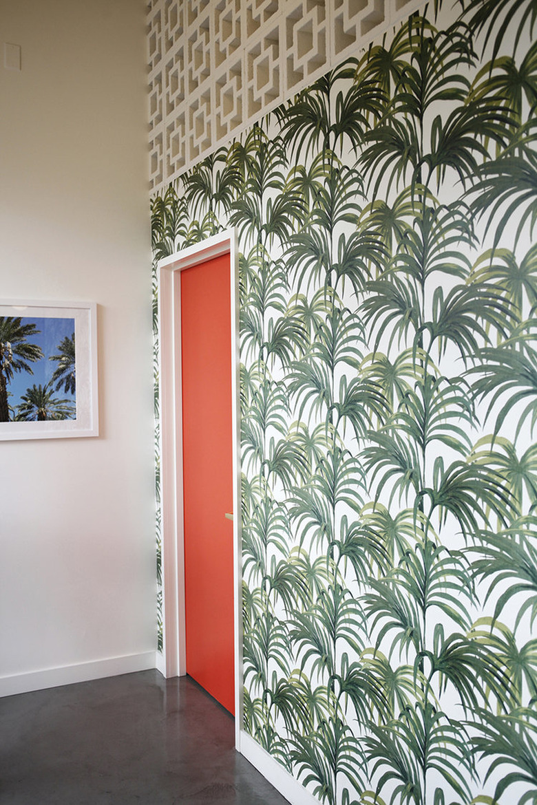 Bright wallpaper with palm design and red door.