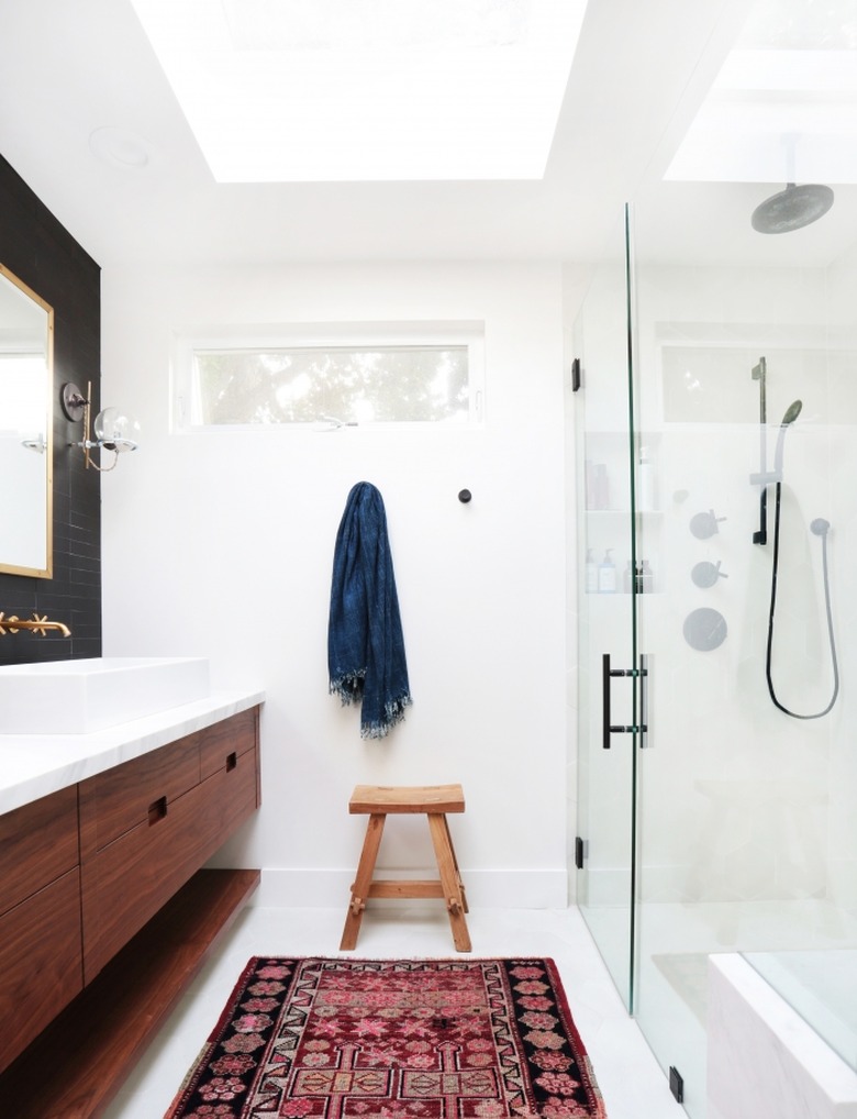 bathroom curtain idea in mostly white bathroom with a wood vanity, black wall behind the mirror, small window and skylight