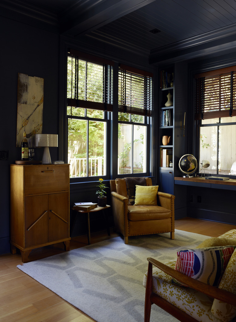 Dark blue painted study with vintage wood furniture and wood floors