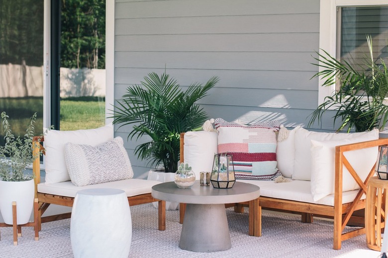 Round gray table with succulent terrariums and white cushioned deck furniture