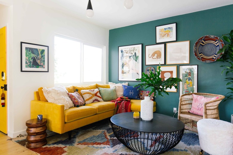 bohemian living room with green accent wall and yellow sofa