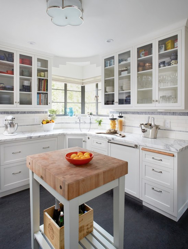 Blue linoleum kitchen flooring with small island topped with butcher block and white cabinets