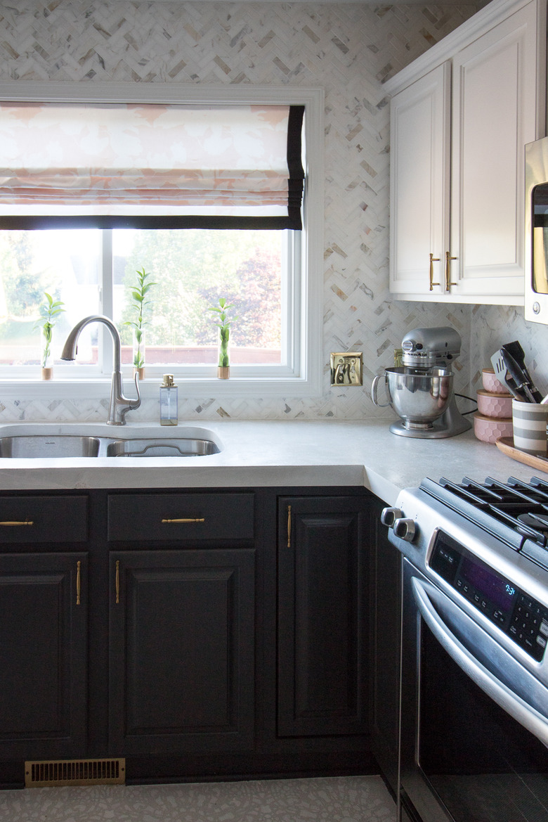 Marble tile herringbone backsplash with black cabinets and sink