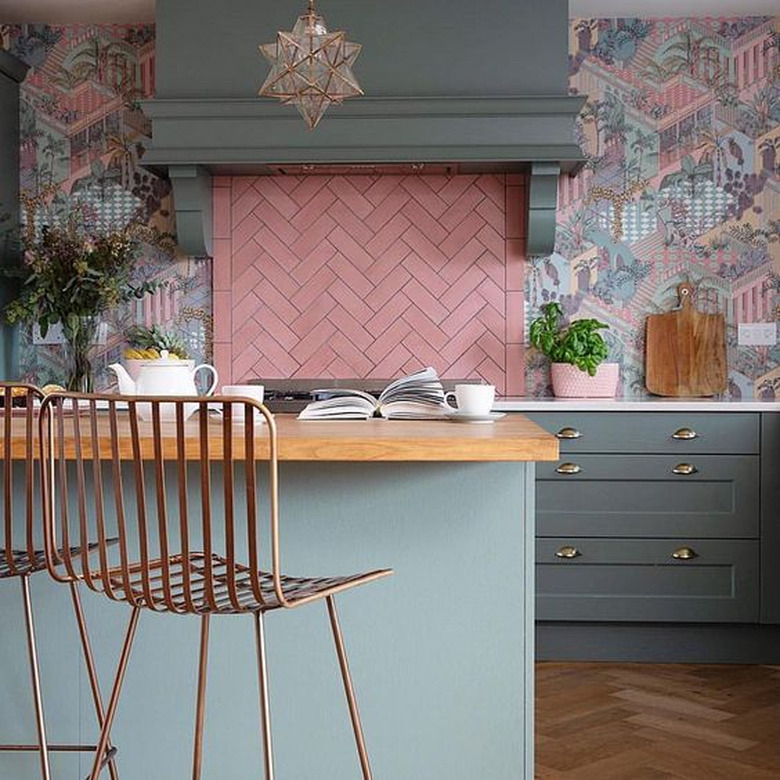 pink pastel herringbone backsplash and muted cabinets with patterned wallpaper