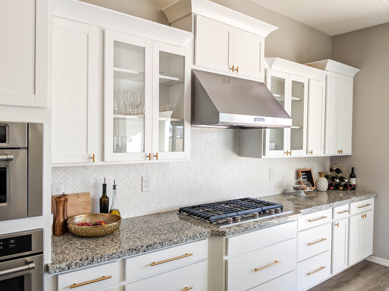 White herringbone backsplash in small tiles with white cabinets