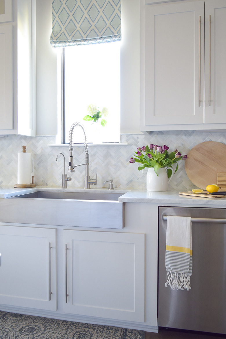 Gray and white tile herringbone backsplash with white cabinets and apron front sink